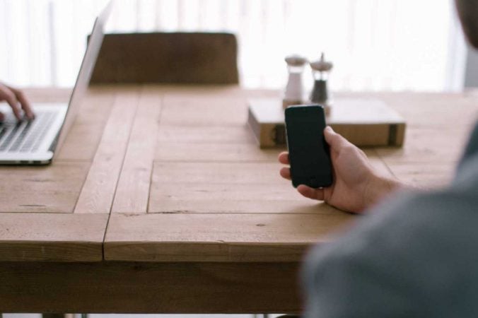 person-smartphone-office-table-676x450